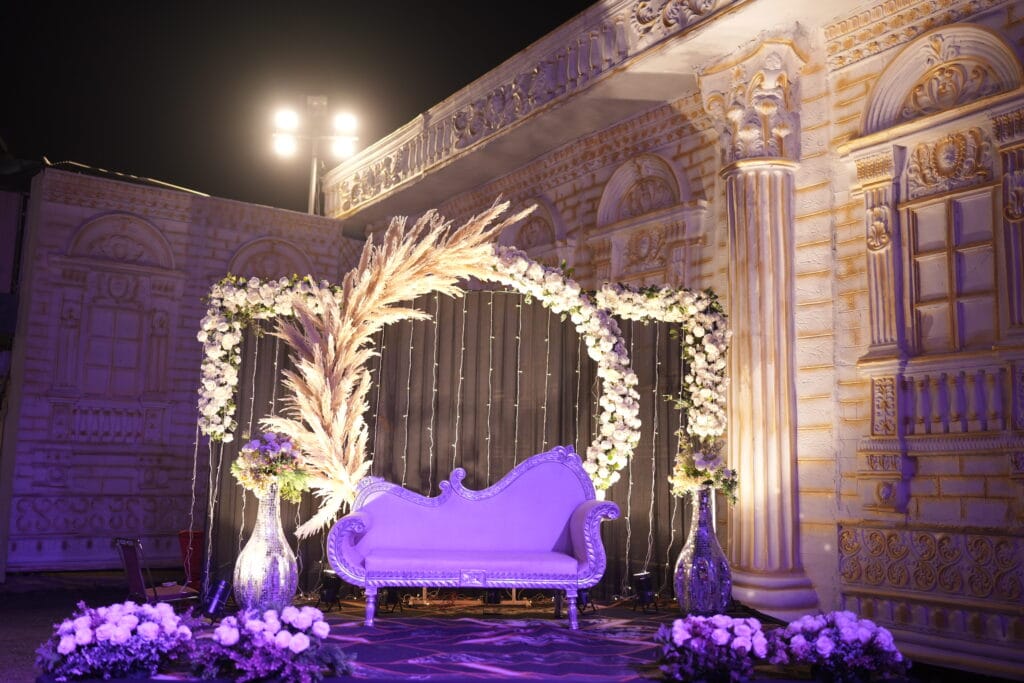Elegant wedding stage decoration with white flowers, pampas grass, and a silver sofa, designed by professional Wedding Plannings in Jaipur